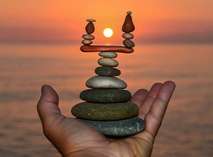 This is a picture of rock statue in someone hands with a sunset behind the hand