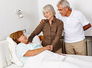This is a picture of a elderly couple visiting a patient