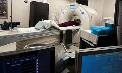 This is a picture of a patient laying down about to get a xray done while a nurse is standing at the patient head talking with them